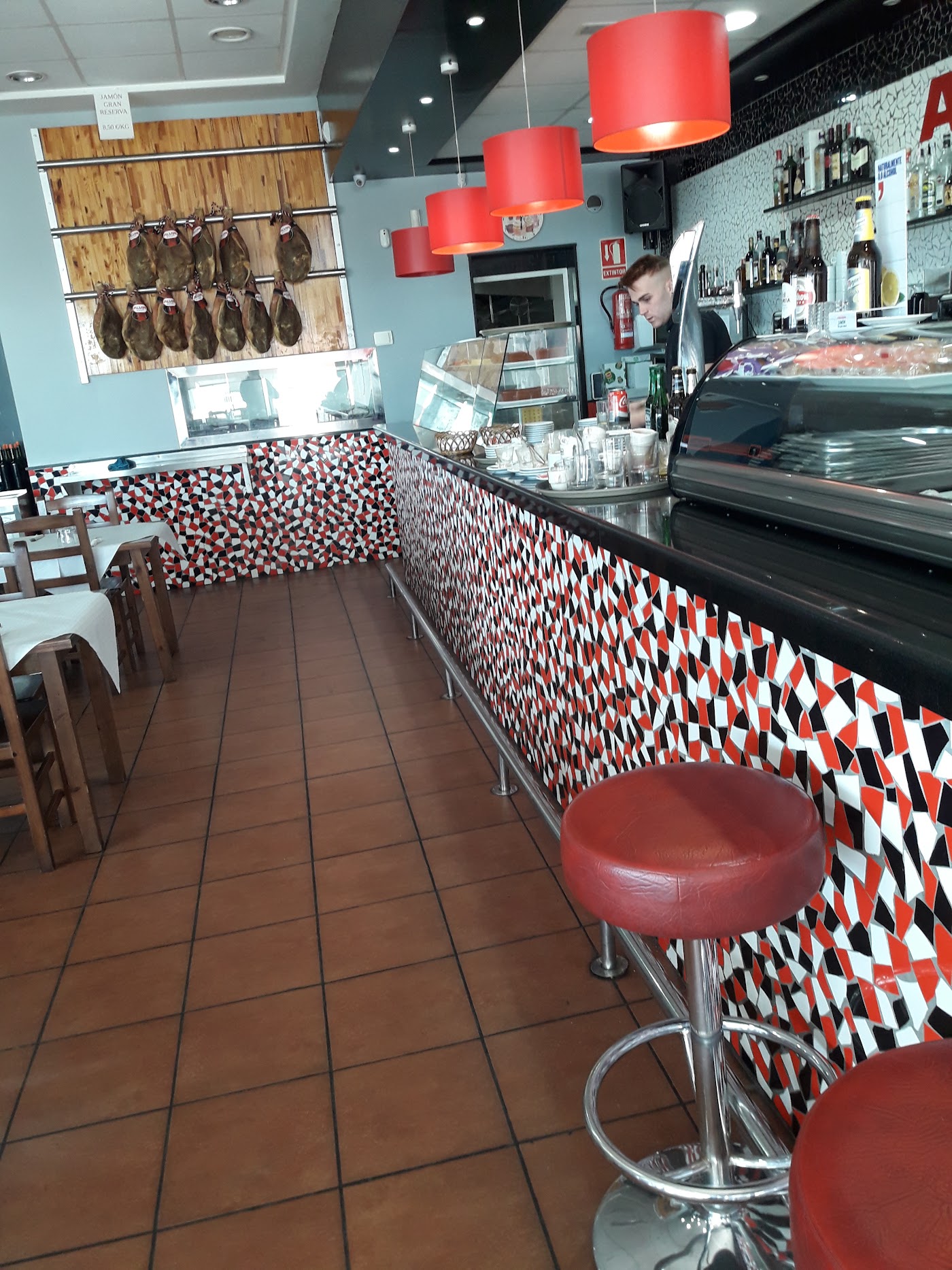 Barra con mosaico rojo, negro y blanco y taburetes rojos