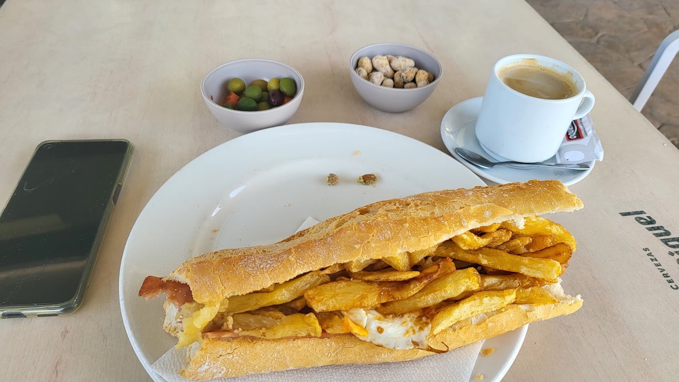 Bocadillo de almuerzo con patatas y huevo, con café y aceitunas