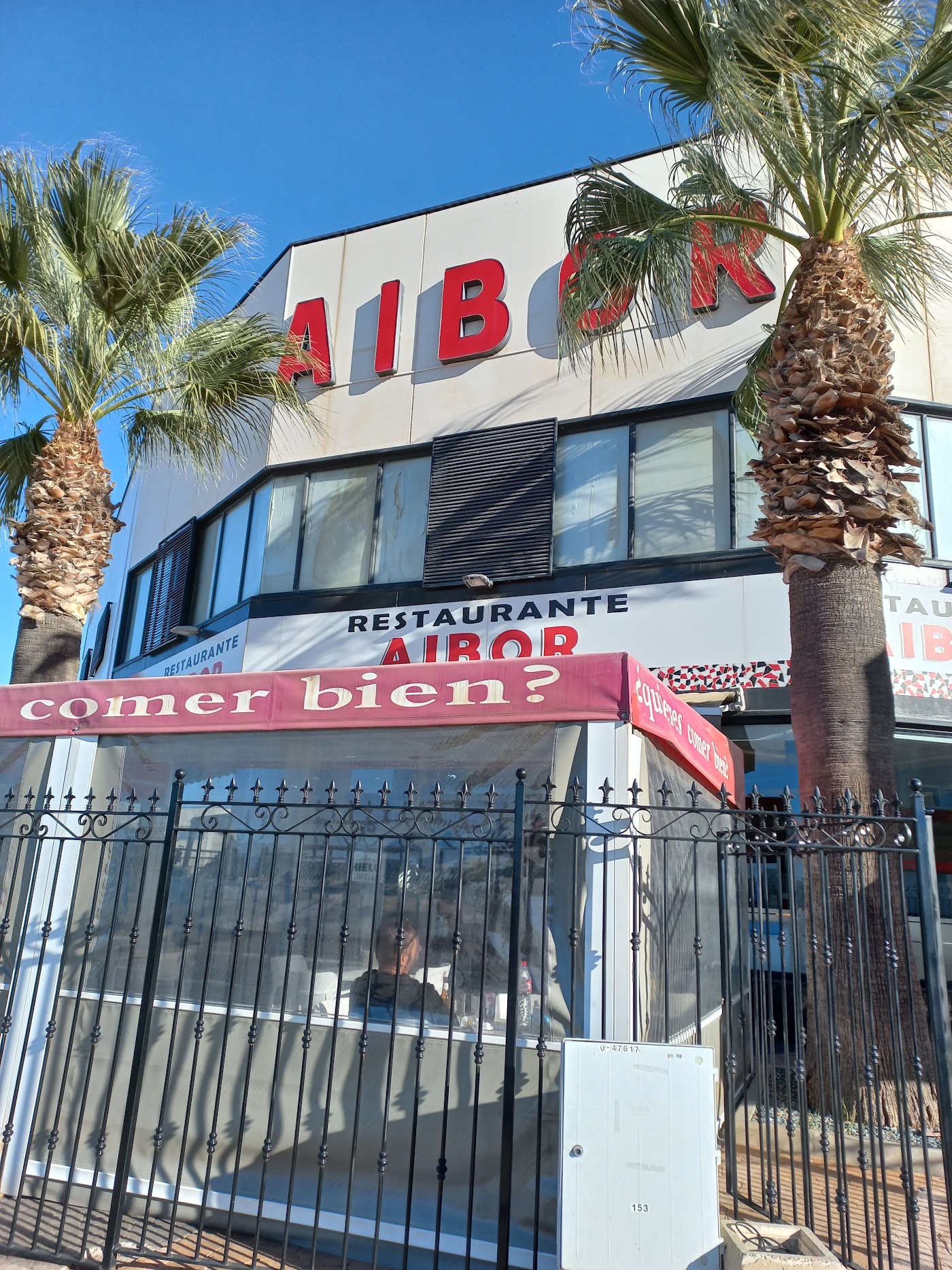 Fachada del Restaurante Aibor con el rótulo rojo y palmeras