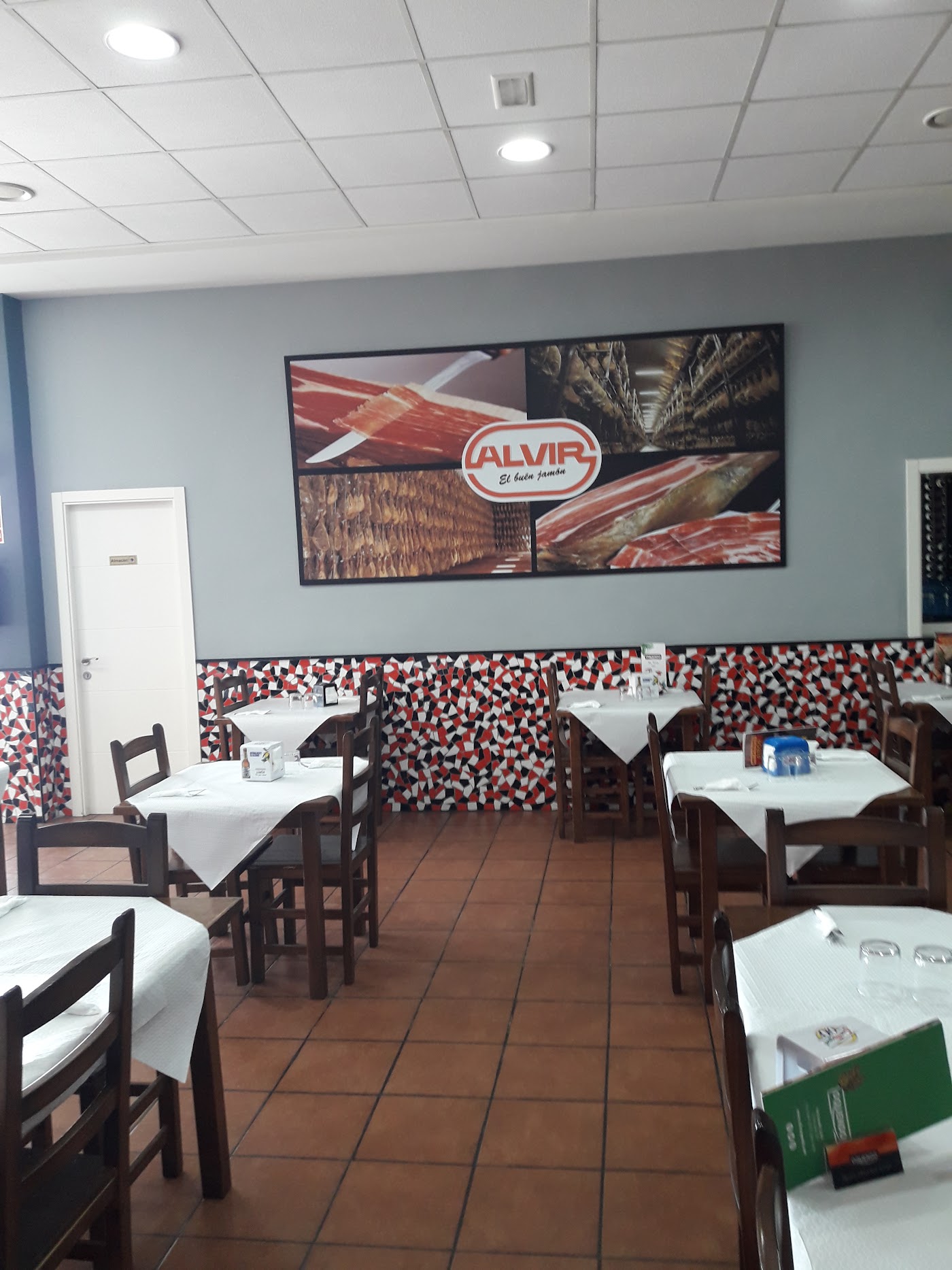 Comedor con mesas de mantel blanco y mosaico en la pared