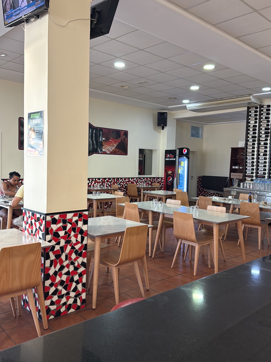 Sala del restaurante con mesas y zócalo de mosaico rojo y negro